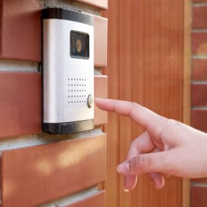 Finger touching a doorbell camera. 