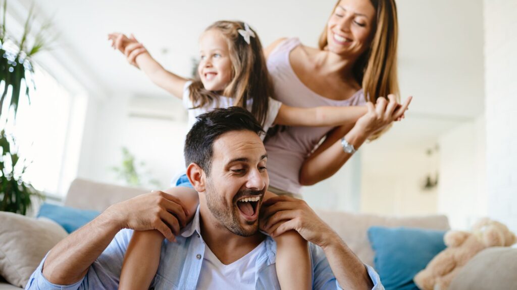 smiling daughter on dad's shoulders in home